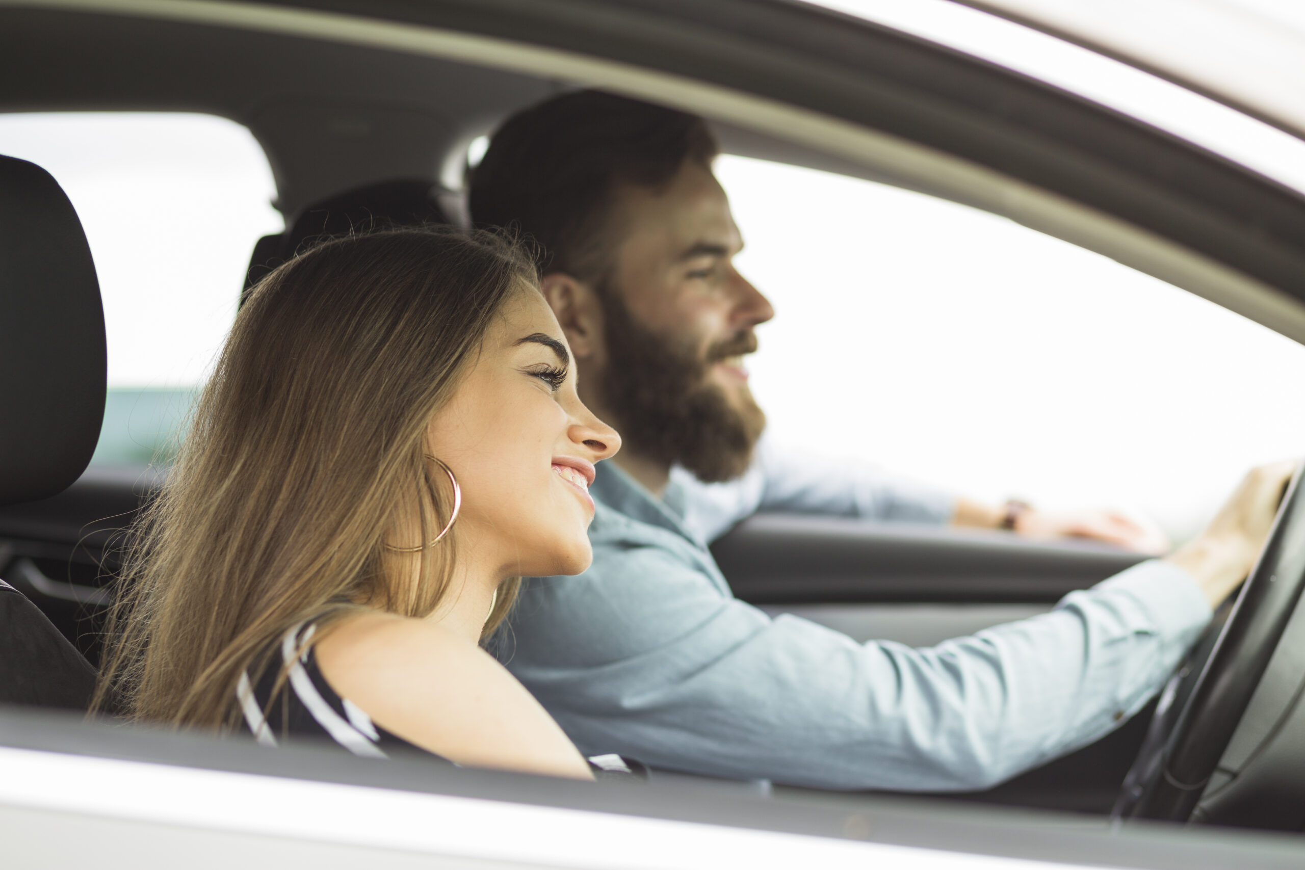 uomo e donna sorridono all'interno di un'automobile
